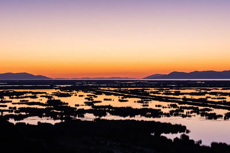 Amanhecer sobre o Lago Titicaca e os juncais perto de Puno
