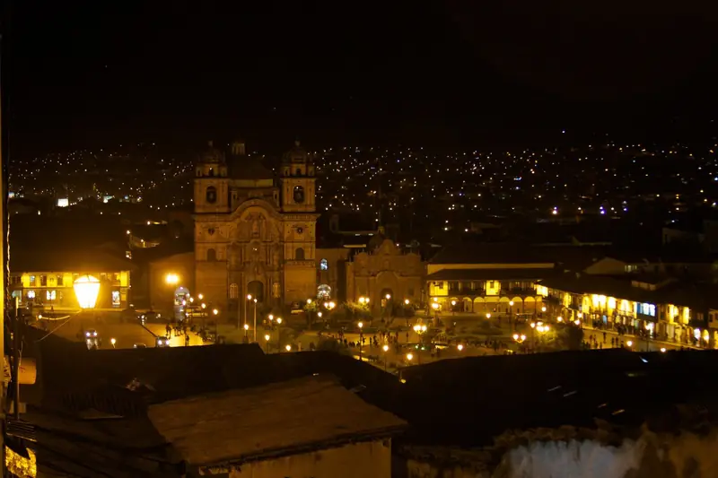 Plaza de Armas de Cusco iluminada à noite, com a igreja da Companhia de Jesus